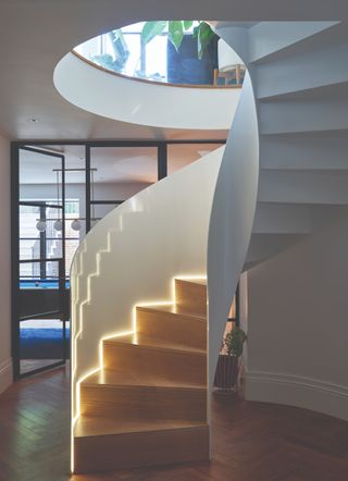 A bespoke spiral staircase with built in lights leads down to an extensive basement space