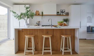 white kitchen with wood panel island granite worktop open shelving bar stools