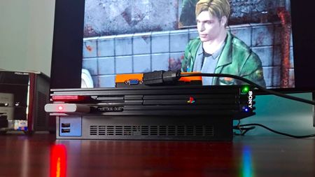 PS2 console with GBS-C upscaler connected via SCART and sitting on top with James from Silent Hill 2 on screen in backdrop.