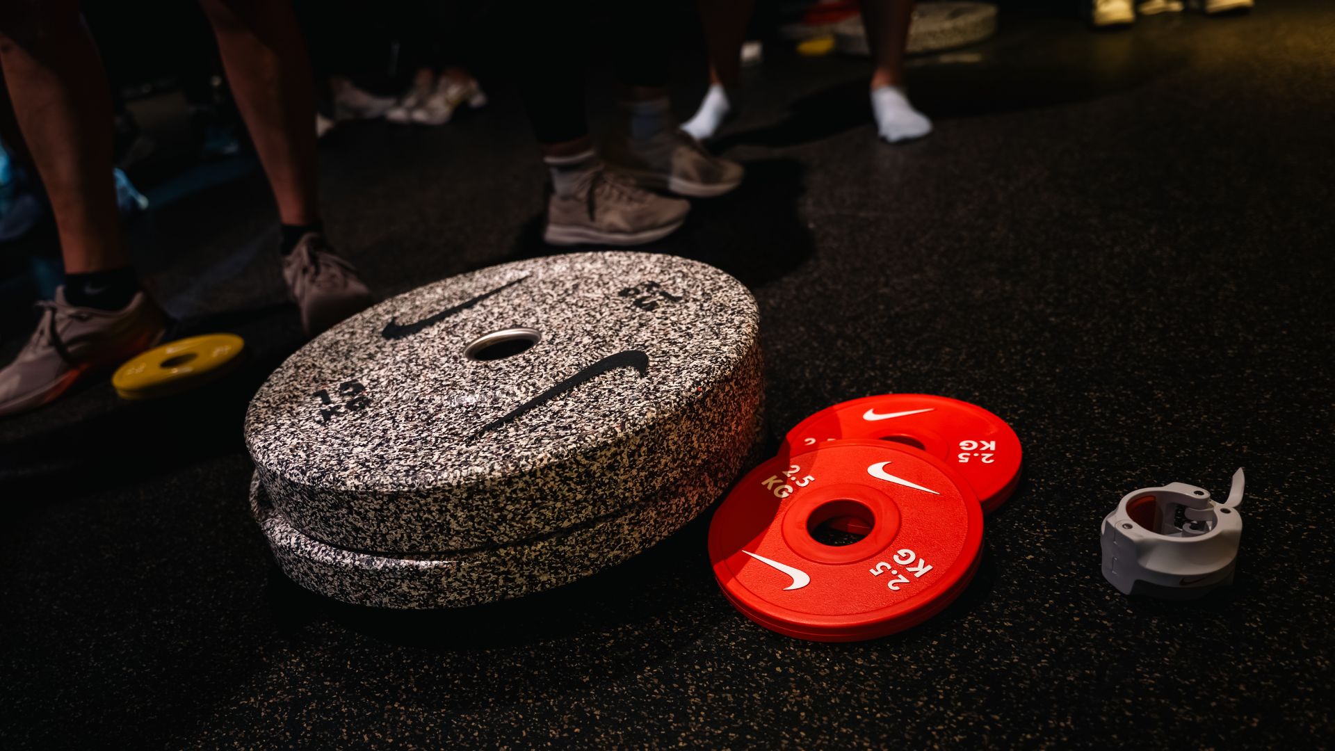 an image of space weights, bar bell weights, and weight clips from Nike all made from their recycled textile waste on the floor in a gym