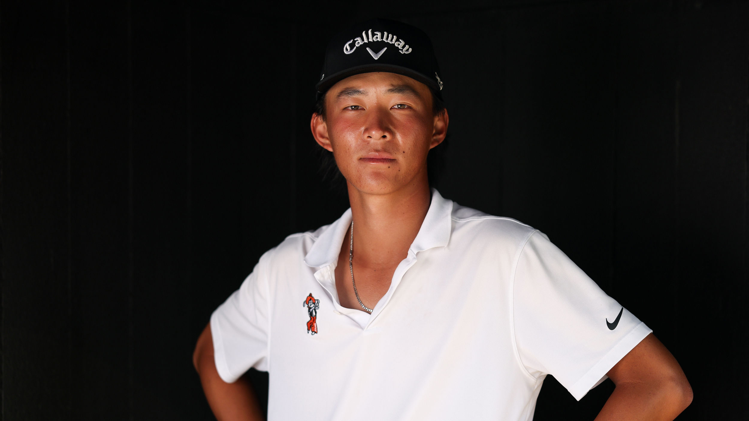 Ethan Fang looks directly at the camera while wearing a black Callaway cap and a white USU polo