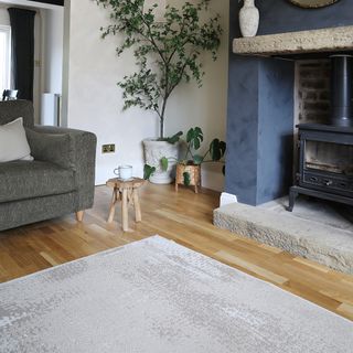 A living room with a blue-painted fireplace and a light grey rug on a wooden floor