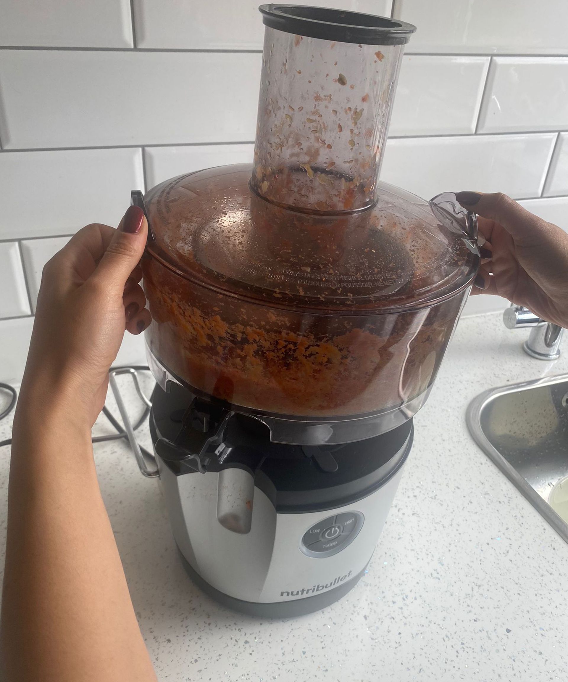 Christina Chrysostomou mengangkat semangkuk bubur dari Nutribullet Juicer Pro di dapur berubin putih