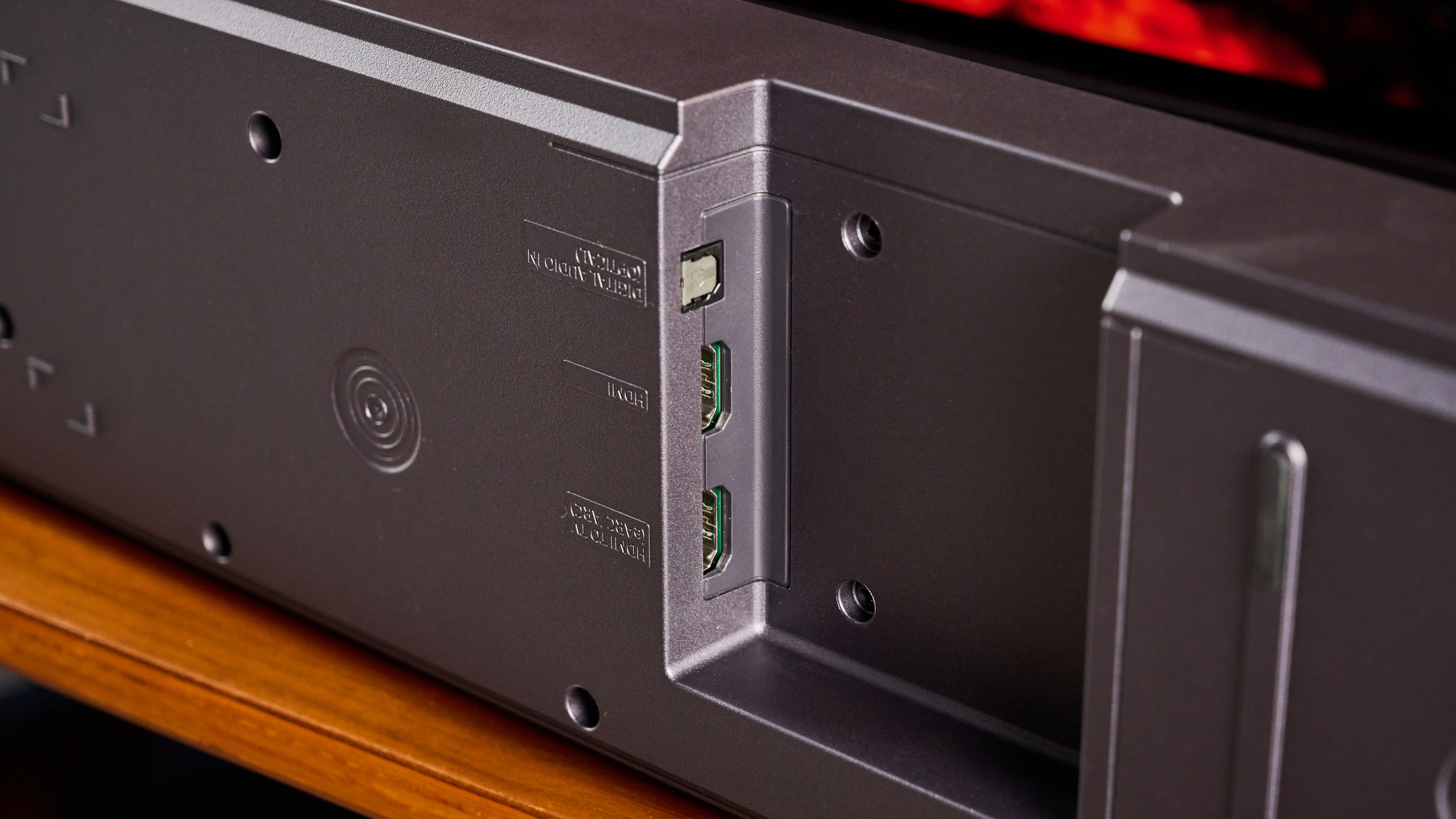 the samsung qs750f soundbar with two rear surround speakers and subwoofer photographed against a blue background and a TV