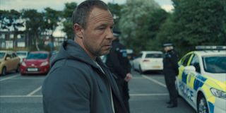 stephan graham as eddie miller in adolescence walking through a parking lot outside of a police station