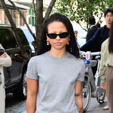 Myha'la wearing a gray t-shirt, blue jeans, black flats, black sunglasses, and a black Chanel handbag