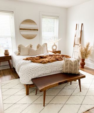 white bed with brown pillows on top of white rug