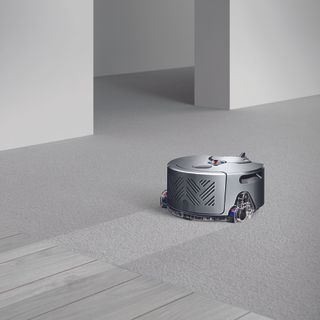 Dyson robot vacuum cleaner cleaning carpet in grey living room