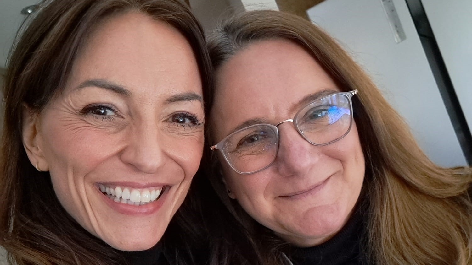 Davina McCall and Lisa Dyke stand with their heads together, smiling for the camera