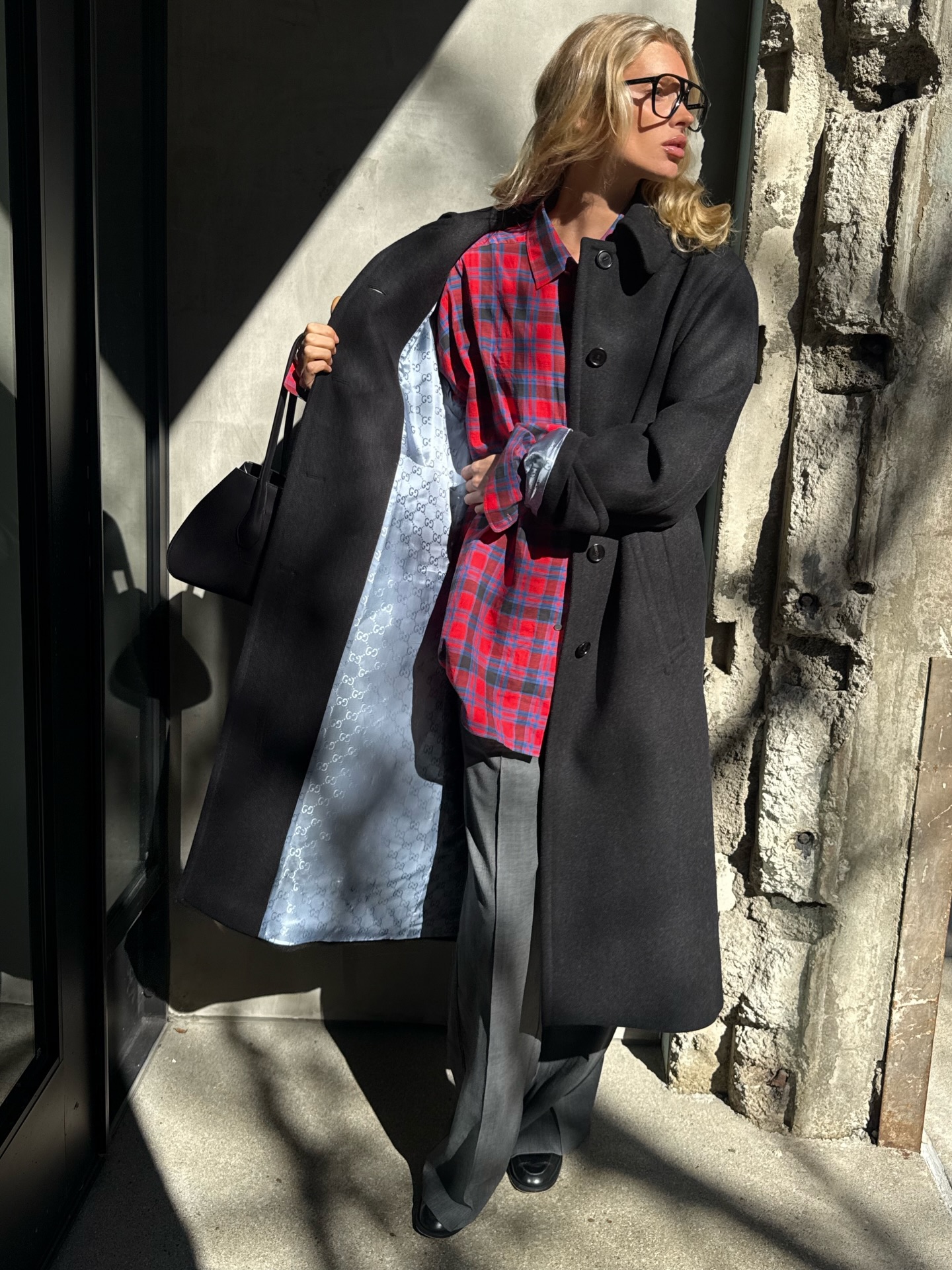 Elsa Hosk wearing a red flannel The Row shirt with a black jacket and gray tailored trousers.
