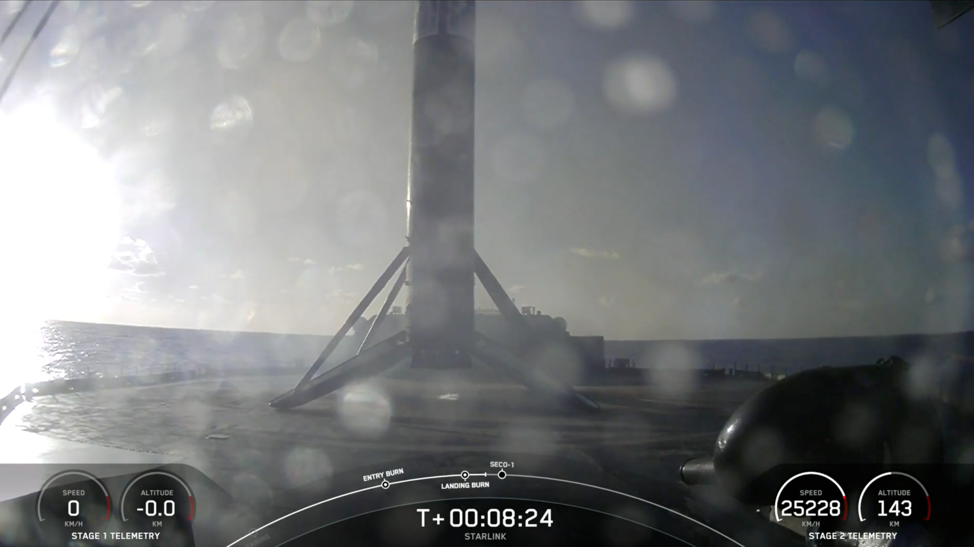 The first stage of a black-and-white SpaceX Falcon 9 rocket sits on the deck of a ship at sea.