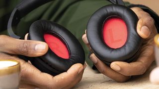 A man cupping the Lindy BNX-60 Bluetooth headphones in his hands