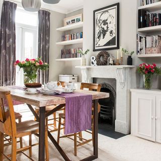 dining room with fire place and book shelves and white wall