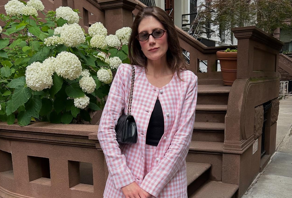 Who What Wear editor Allyson Payer wearing pink tweed skirt suit, black tank top, sunglasses, and black bag and standing in front of New York residence.