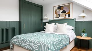 A bed with graphic bedding and green wood paneling