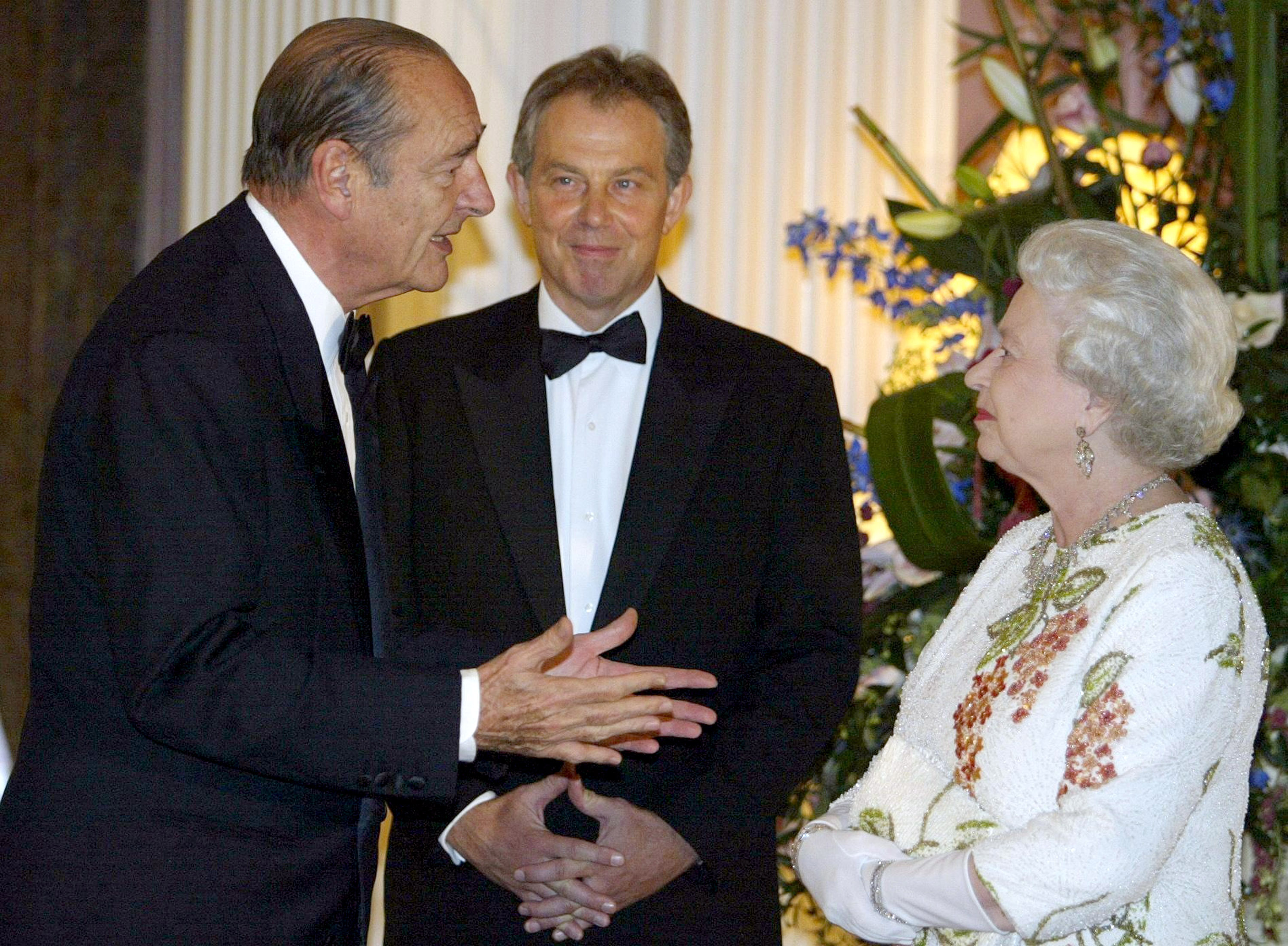 Queen Elizabeth wearing a white dress talking to French President Jacques Chirac and Britain's Prime Minister Tony Blair
