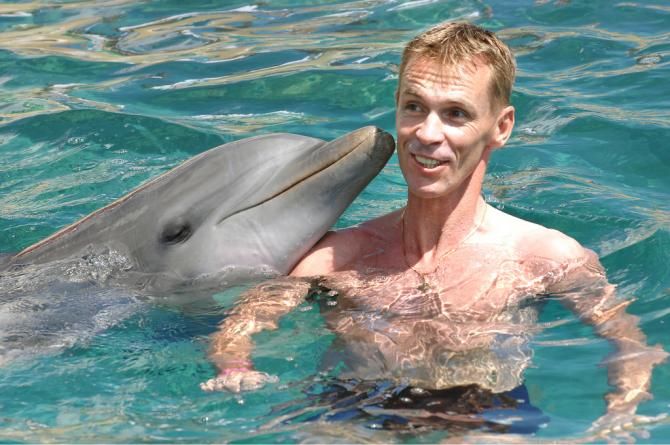 Eric Dekker looking a little concerned by the dolphin nibbling at his ear