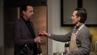 Gabriel LaRoche handing Timothy McGee a glass of wine in his kitchen in NCIS