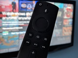 Amazon Fire TV 4K remote with Hulu app on TV in background