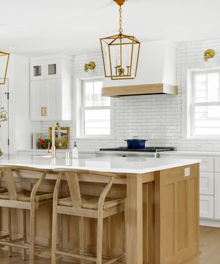 A white marble kitchen with a wooden island and metal light fixtures