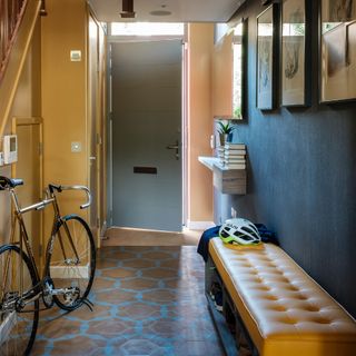 A hallway with a yellow and a black wall and a storage seating bench with yellow upholstery