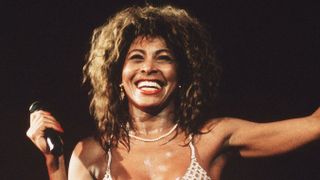 Tina Turner smiles on stage during a performance at Wembley Stadium in 1990.