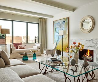 living room with white sofas and white walls with fire lit and big artworks