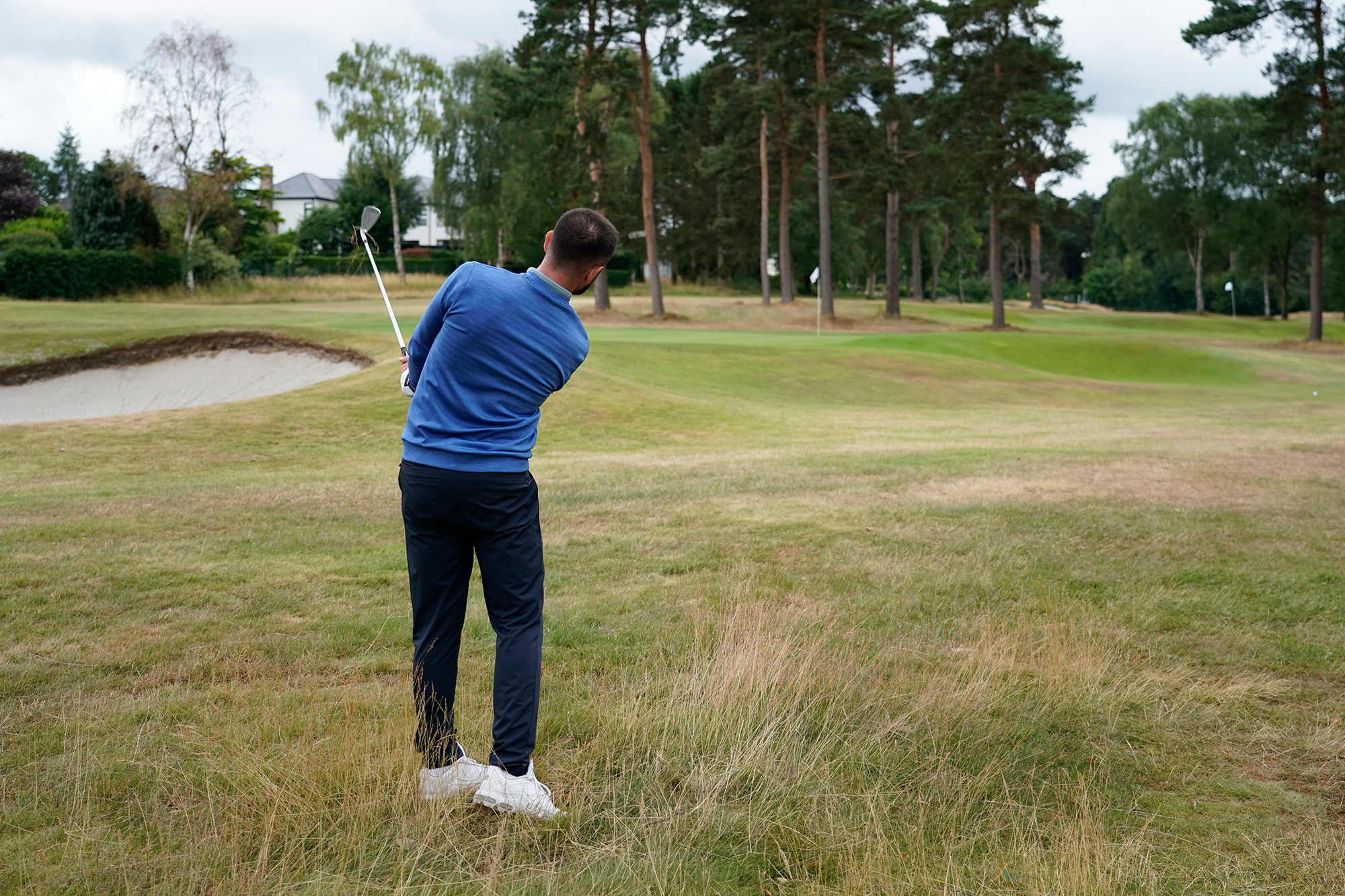 Baz Plummer hitting a pitch shot from inside 50 yards over heavily contoured run off areas and long grass, towards a tucked pin on the first green at Sand Moor Golf Club