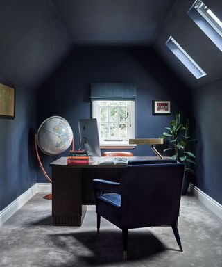 dark navy blue home office with desk in centre and large globe