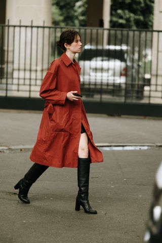 A woman wearing black knee high boots and a red coat