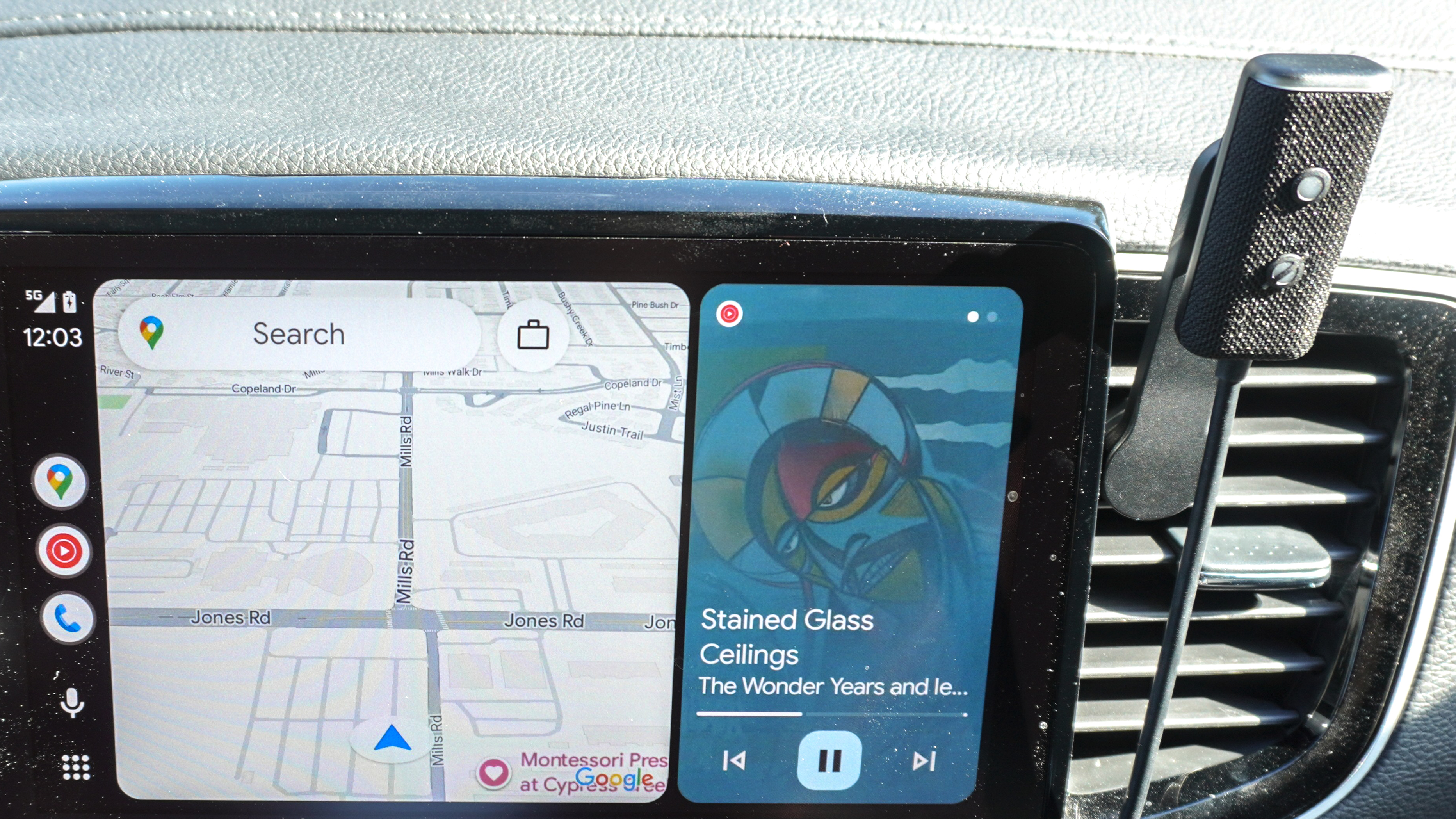 An Echo Auto (2nd Gen) mounted on the fan vent next to an in-car infotainment system