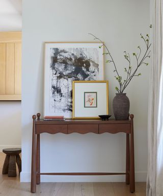 A wooden console table in a white entryway