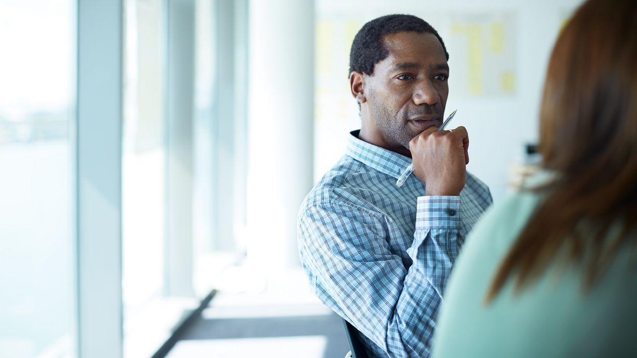 A man listens intently while an off-screen person talks to him.