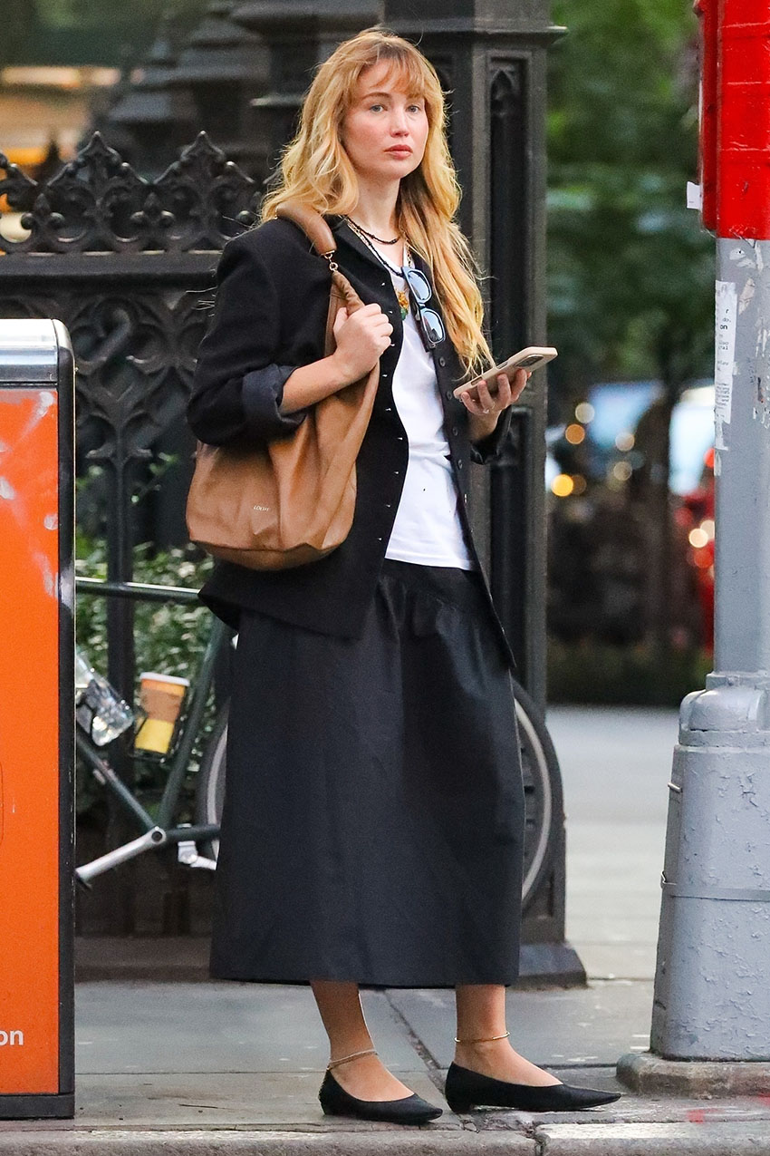Jennifer Lawrence wearing a black button-up, white T-shirt, black skirt, black flats, and brown leather bag