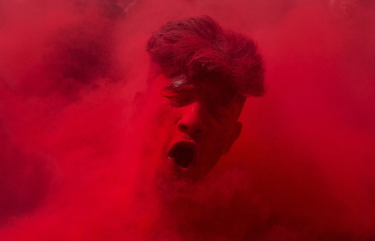 An Indian reveler, face smeared with colored powder, dances during celebrations marking Holi, the Hindu festival of colors.