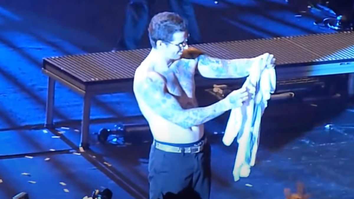 M Shadows on stage holding a t-shirt of The Rev