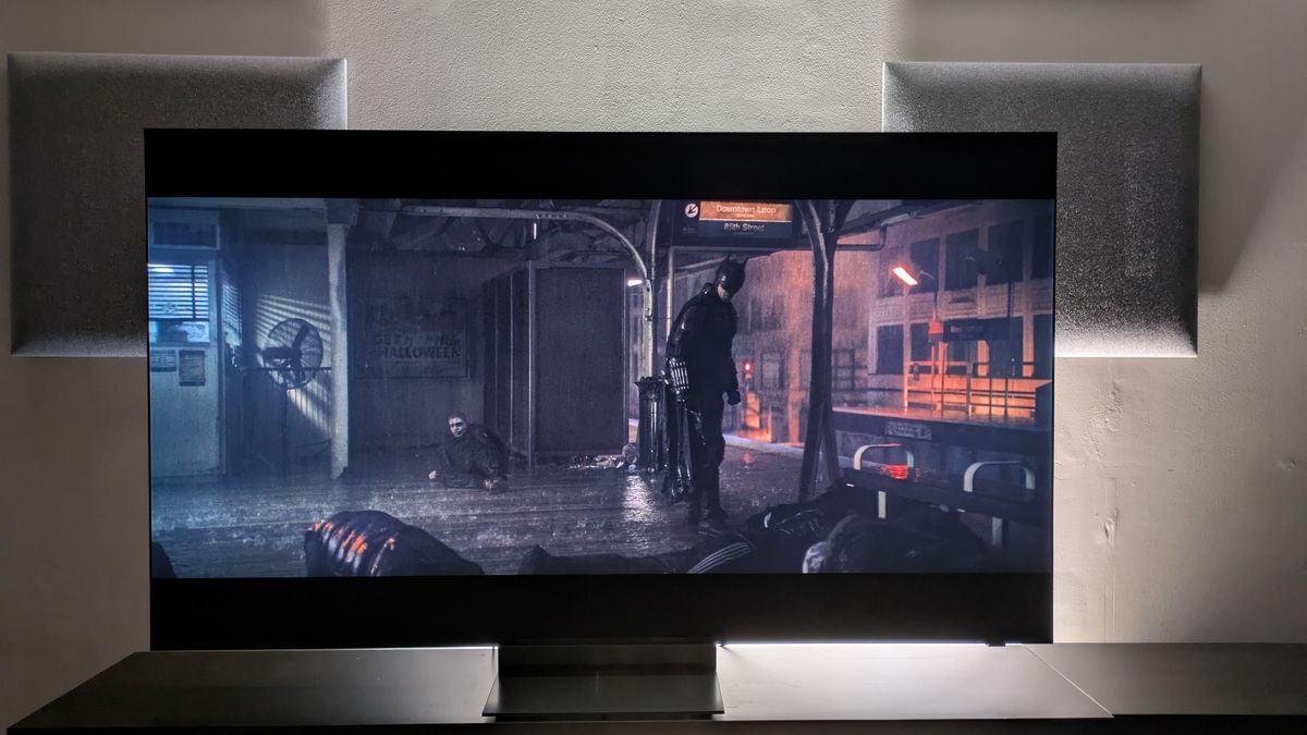 Samsung R95H with shot of Batman standing on subway platform from The Batman on screen. R95H shows excellent detail and contrast
