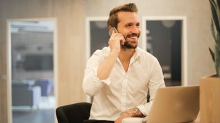 Smiling man talking on the phone in an office