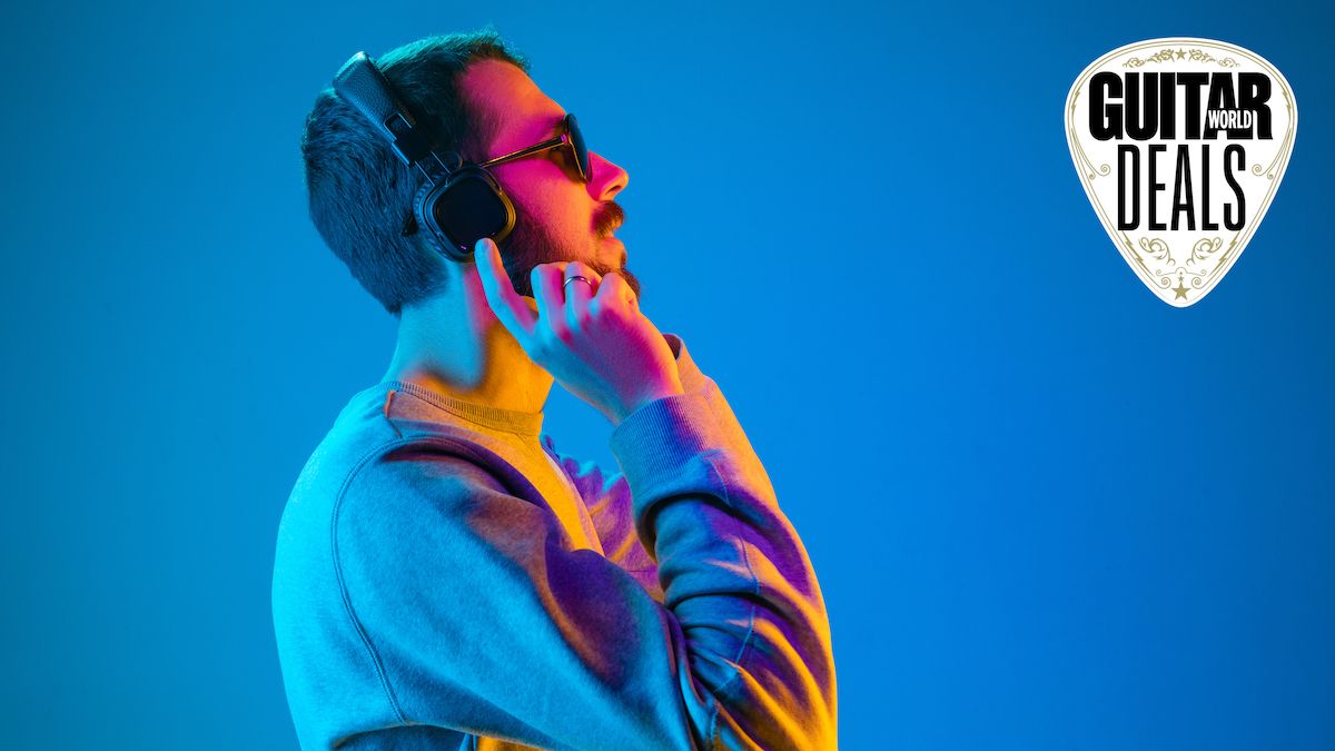 Man wearing headphones and sunglasses stands against a blue background