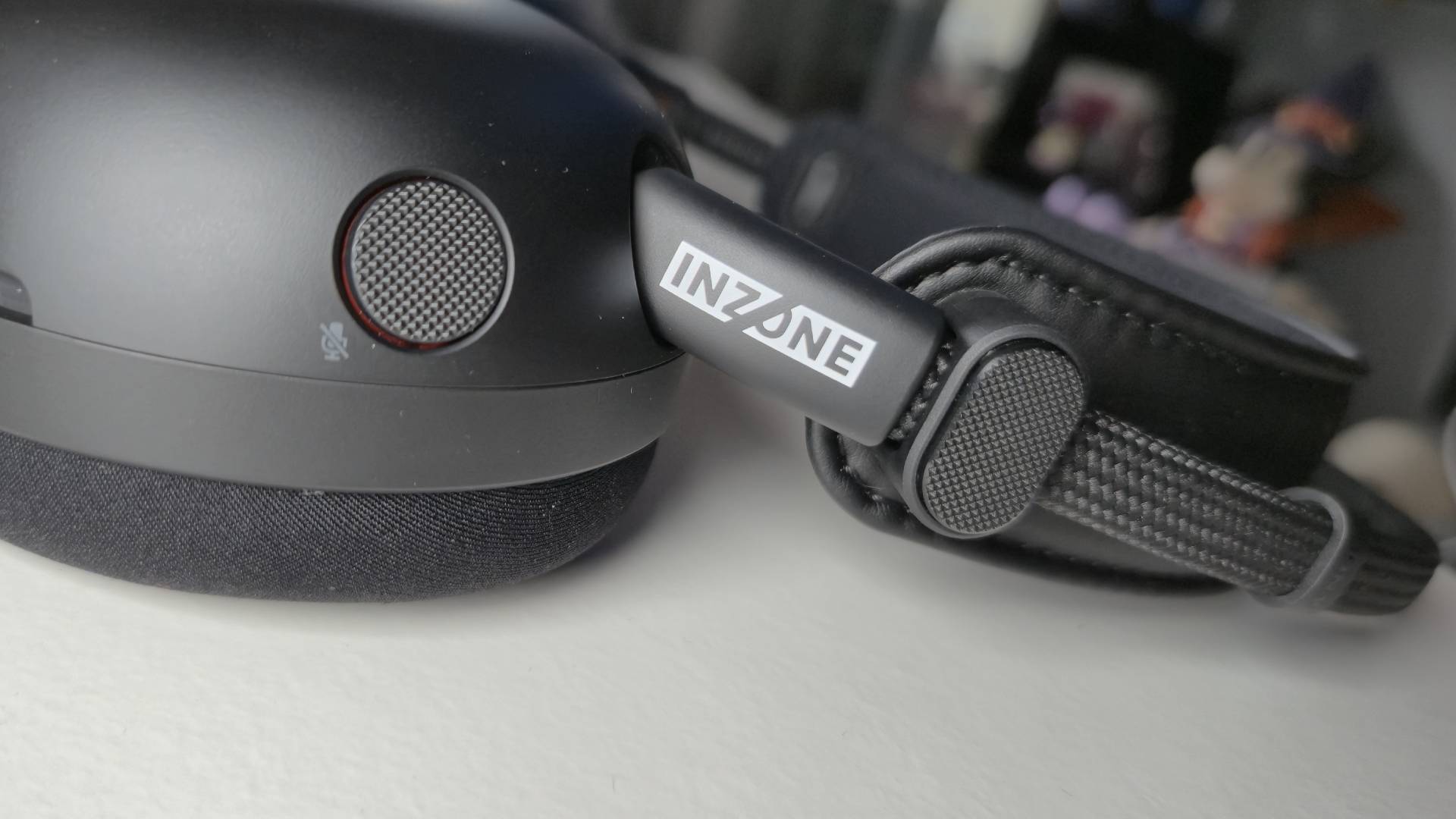 Photo of the side of a black headset, showing a textured mute mic button.