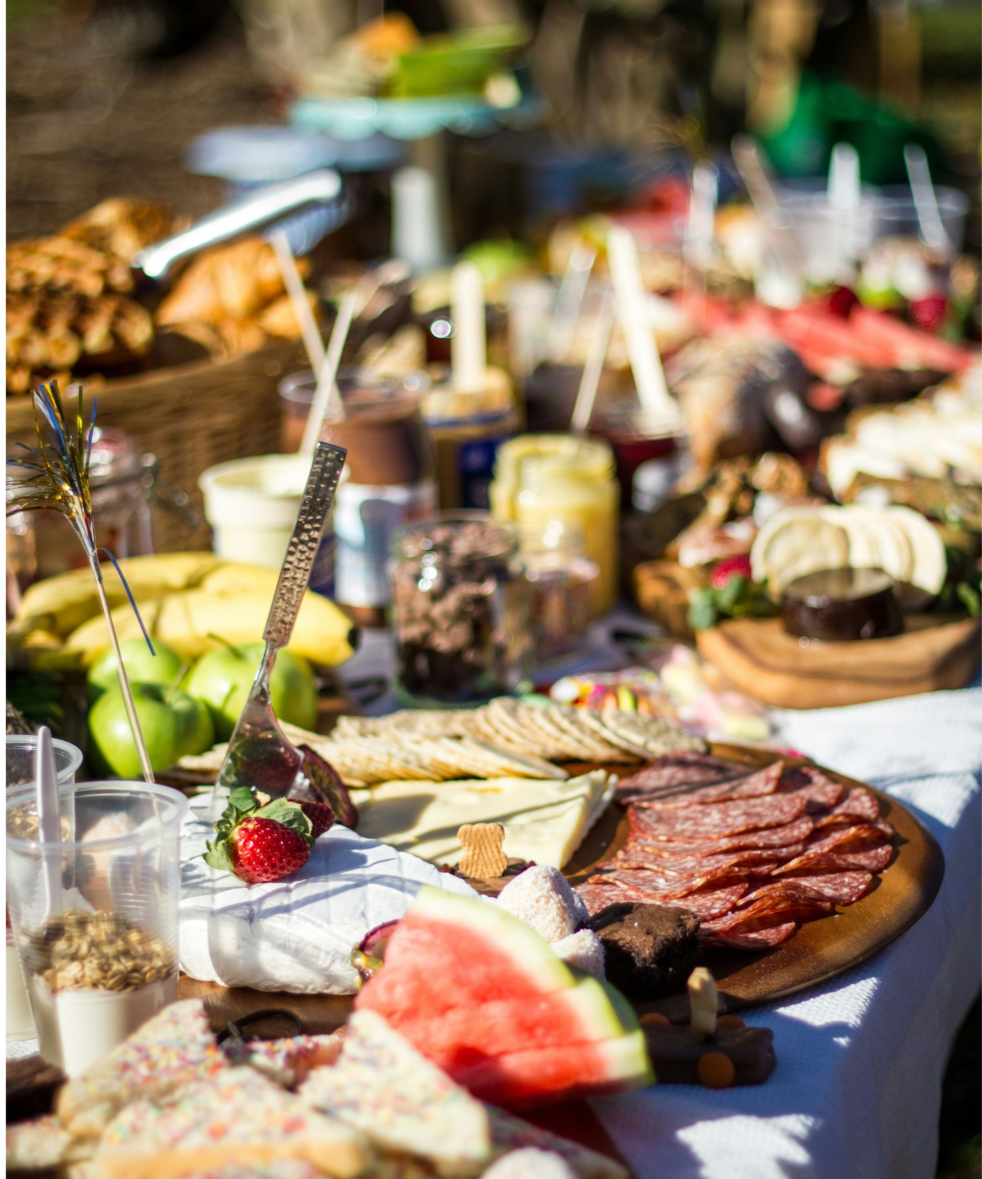 Table of summer appetizers including meats, cheeses, olives and watermelon