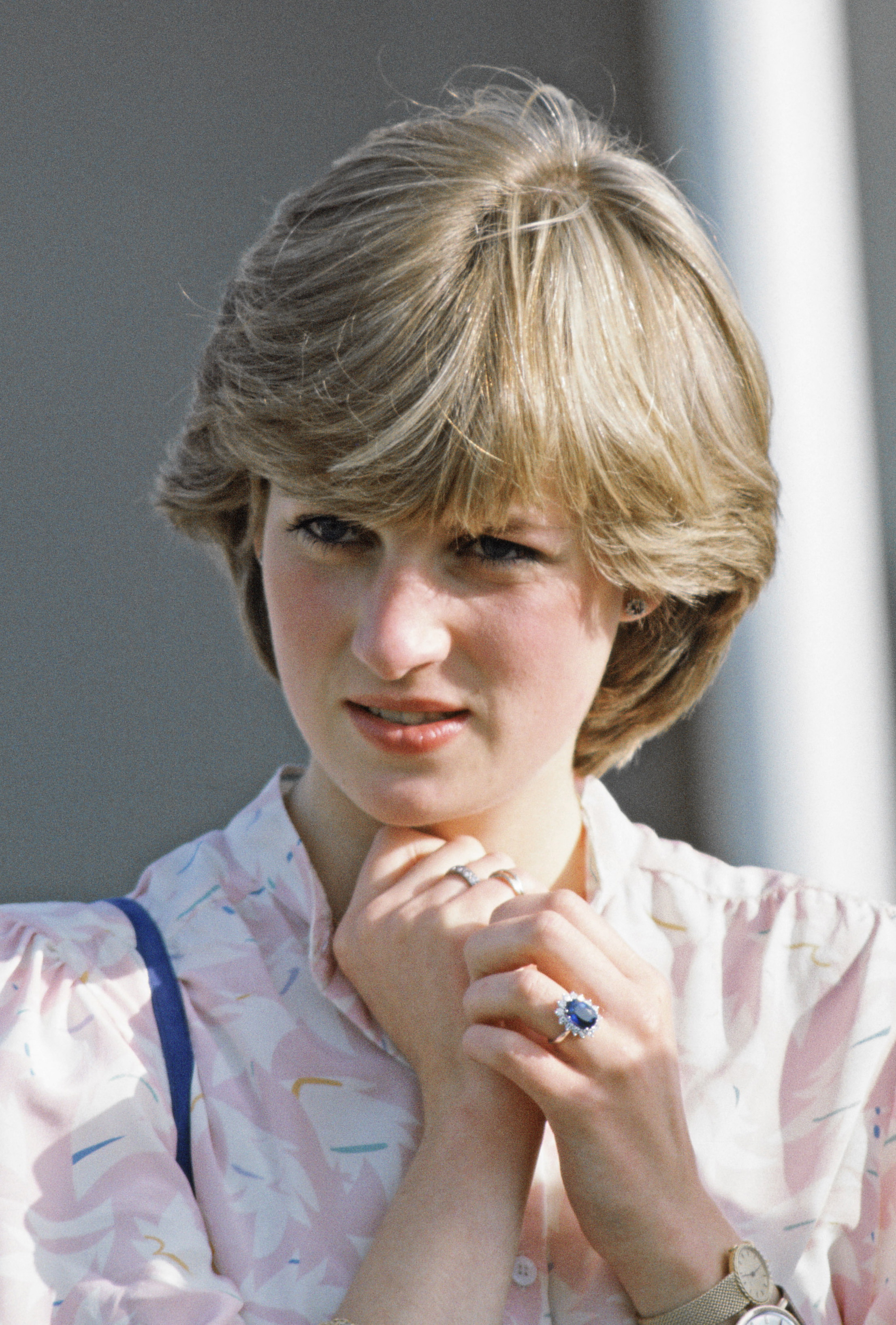 Diana Spencer wearing her engagement ring and holding her hands up to her neck
