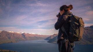 Best camera backpacks: Image shows woman holding camera with large rucksack on back