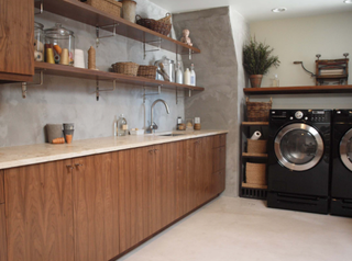 Off-white countertop over wooden counters in laundry room. The cabinets are a wood oak texture with open shelving above.