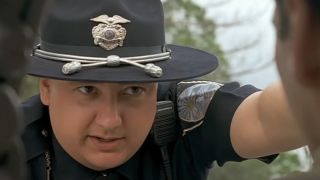 A cop talks into Truman's window about what's going on.