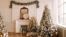 A living room with multiple Christmas trees and a hanging garland