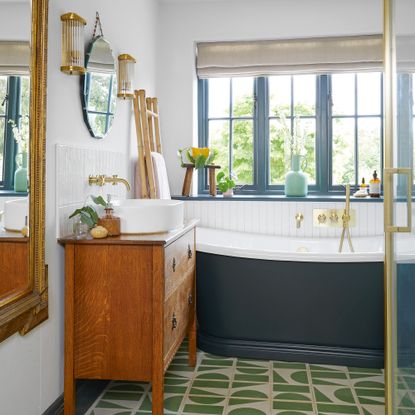 bathroom with panelled walls and green and white floor tiles and dark blue rolltop bath