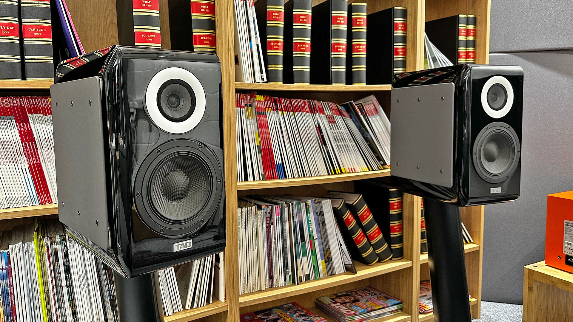 TAD ME1TX standmount speakers on stands in front of bookcase