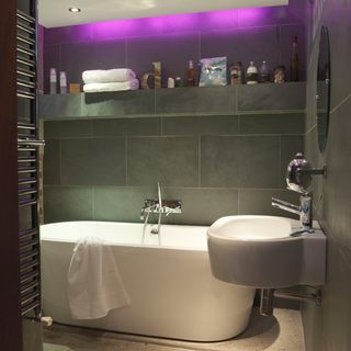 bathroom with grey tiles wall white bathtub and wash basin