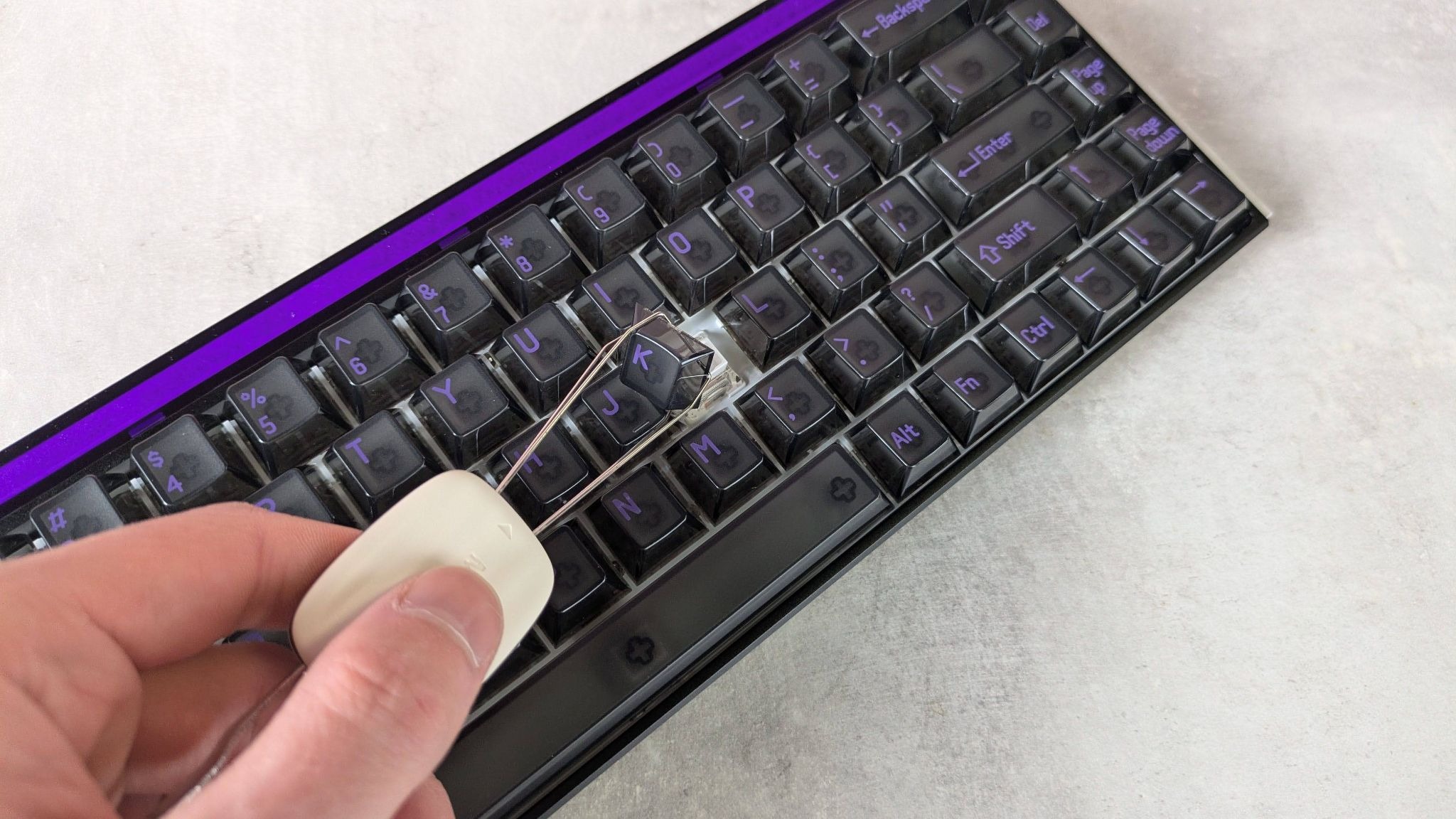 Keycap in keycap removal tool with MelGeek Made68 Ultra V2 behind it, on a desk